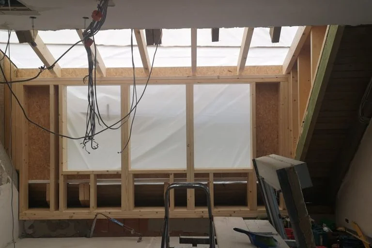 Altbauraum während der Sanierung mit freigelegtem Mauerwerk und neuer Wand